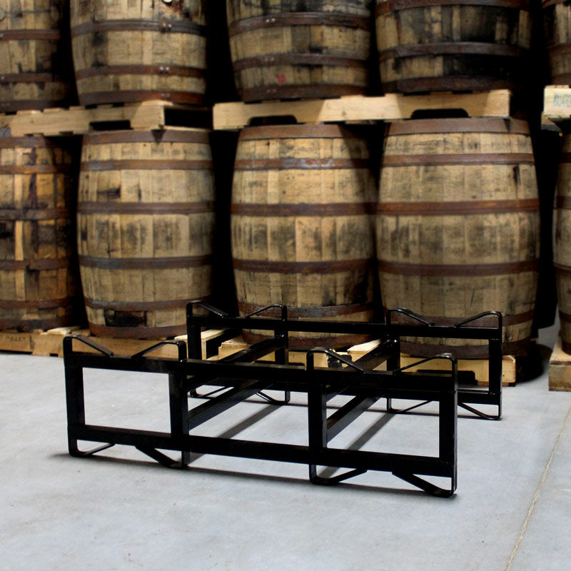 NEW 7", 2-Barrel, Double Bar Steel Rack (Black) on floor in front of barrels on pallets