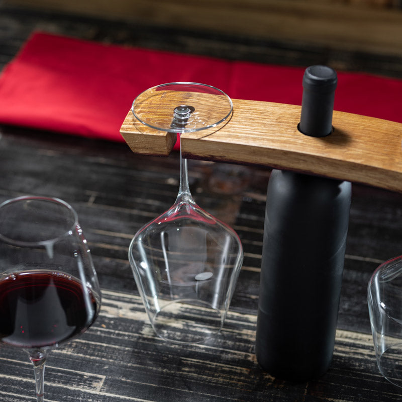 View of glass with wine and a holder holding a wine bottle and other wine glasses