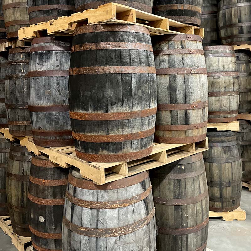 Gray, weathered decor furniture grade whiskey barrels with rusted rings stacked on pallets