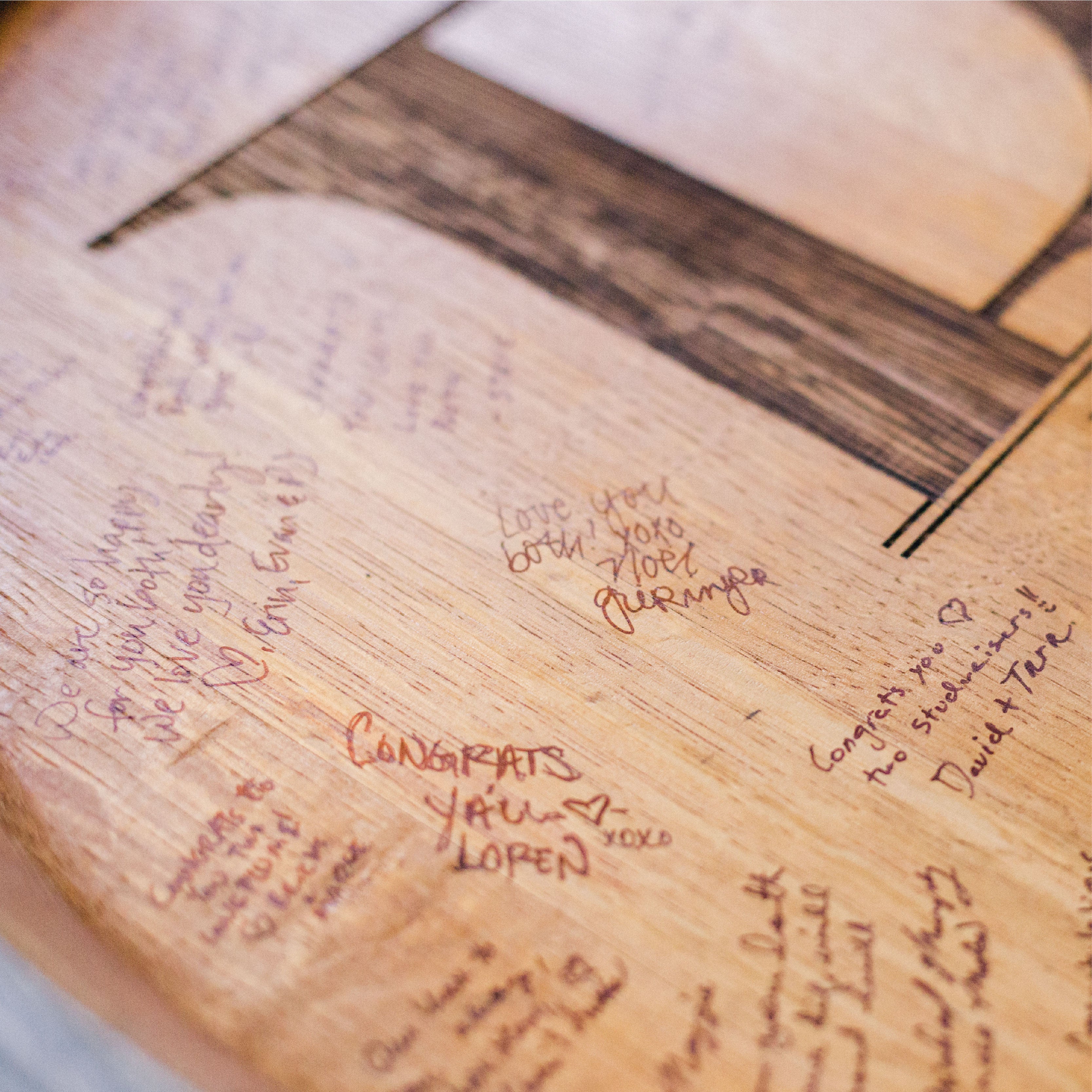 Signatures of people who have signed a couple's engraved barrel head wedding guestbook