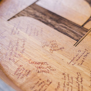 
                  
                    Signatures of people who have signed a couple's engraved barrel head wedding guestbook
                  
                