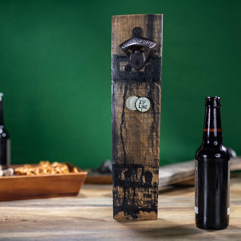 
                  
                    Whiskey Stave Bottle Opener with bottle caps sticking to magnet on stave and beer bottle next to opener
                  
                